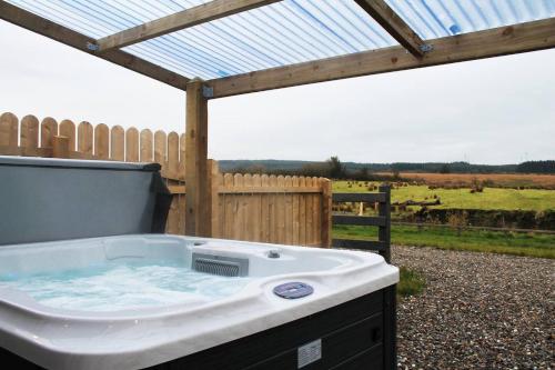 a jacuzzi tub in a backyard with a fence at Forest View Cottage - Private Hot Tub in Ballynameen