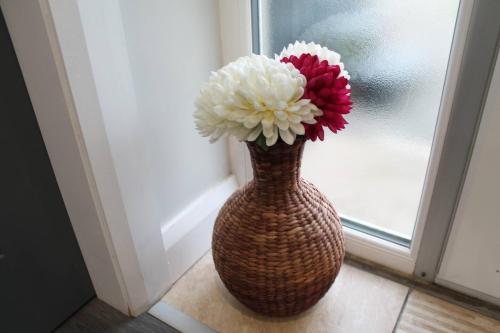 a vase with white and red flowers in a window at Forest View Cottage - Private Hot Tub in Ballynameen