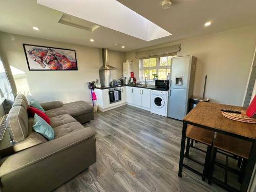 a living room with a couch and a kitchen at Forest View Cottage - Private Hot Tub in Ballynameen