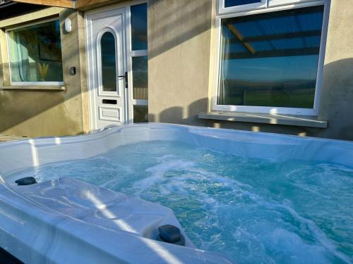 a large hot tub in front of a house at Forest View Cottage - Private Hot Tub in Ballynameen