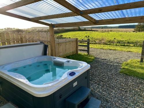 a hot tub under a pergola in a yard at Forest View Cottage - Private Hot Tub in Ballynameen