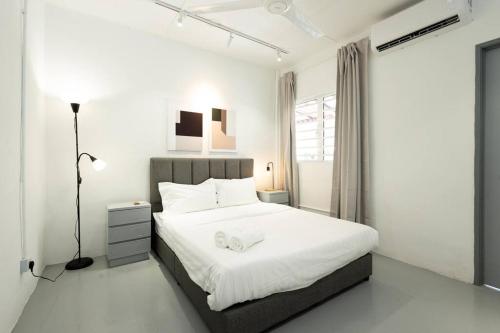 a white bedroom with a large bed and a lamp at Mono Ipoh - Bercham, 2 parking, sleep 10, Lost World Tambun in Ipoh