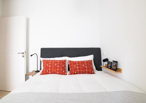 a bedroom with a white bed with red pillows at Elegant Apt 50meters Close Acropolis in Athens