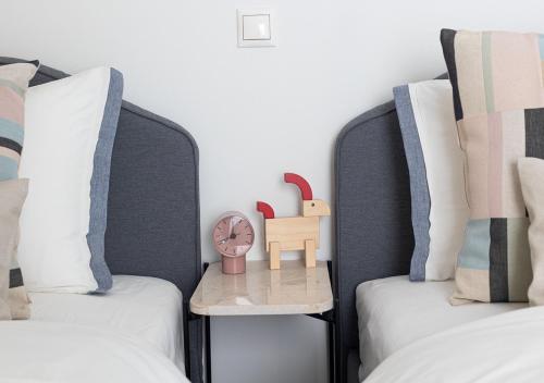 two beds with pillows and a clock on a table between them at Elegant Apt 50meters Close Acropolis in Athens