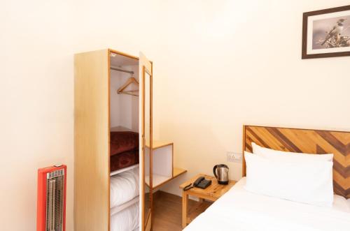 a small bedroom with a bed and a closet at Prakriti-The Retreat in Gangotri
