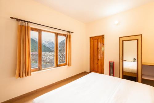 a bedroom with a bed and a window at Prakriti-The Retreat in Gangotri