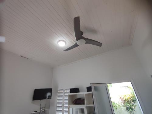 a ceiling fan in a white room with a window at 7 COCOTIERS F2 terrasse jardin plage privée avec vue mer in Ambaro