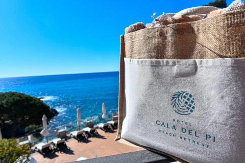 a bag sitting on a railing overlooking the ocean at Hotel Cala del Pi - Adults Only in Platja  d'Aro