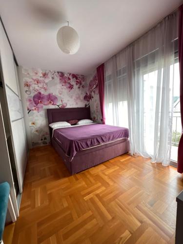 ポドゴリツァにあるApartman Zvjezdiceの花柄の壁紙を用いたベッドルーム1室(紫色のベッド1台付)