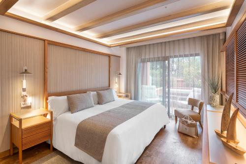 a bedroom with a large bed and a large window at Hotel Cala del Pi - Adults Only in Platja  d'Aro