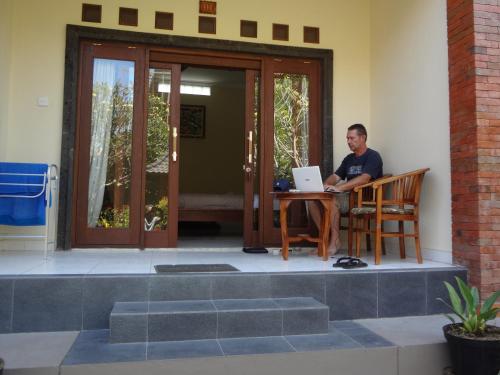a man sitting at a table with a laptop at Nami House in Ubud