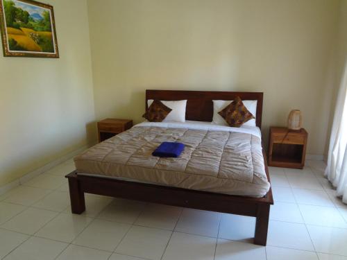 a bedroom with a large bed with a blue pillow at Nami House in Ubud