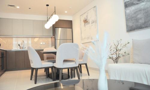 a dining room and kitchen with white chairs and a table at Sea Breeze Oasis in Dubai