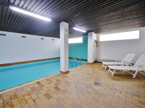 uma piscina num quarto com cadeiras brancas em Appartement HappyNest*** mit Hallenbad em Willingen