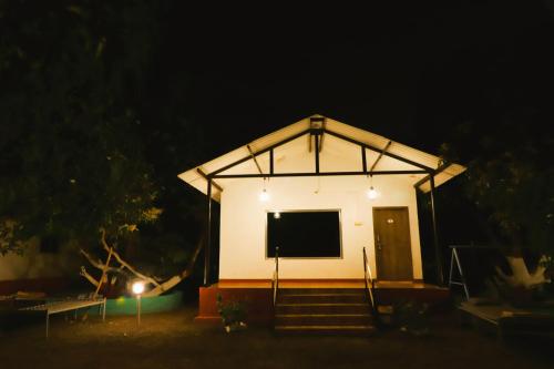 a small white building with a large screen at night at Danak Farm And Resort in Sasan Gir