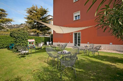 a group of chairs and tables in front of a building at Bike & Wind Hotel Villa Maria - Happy Rentals in Nago-Torbole