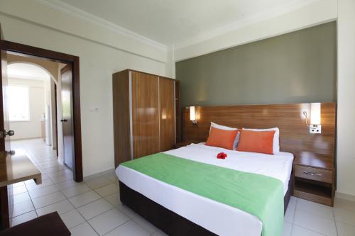 a bedroom with a large bed with orange and green sheets at Sunlight Garden Hotel in Side