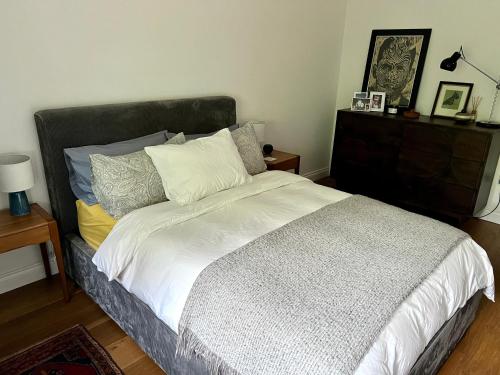 um quarto com uma cama com lençóis brancos e almofadas em Urban Oasis Chic 1BR Flat with Spacious Garden em Londres