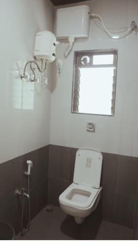 a bathroom with a toilet and a window at Anant Villa & Resorts in Nagaon