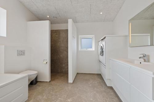 a white bathroom with a toilet and a sink at Newly Built Luxury Holiday Home, Sensommervej 4 in Løkken