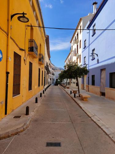 an empty street with yellow and white buildings at Casa Mayago, terraza y solárium in Pego
