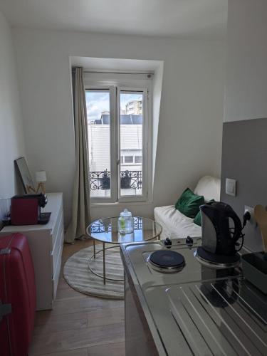 - un salon avec une table, un canapé et une fenêtre dans l'établissement Studio Cosy Proche Métro, à Paris