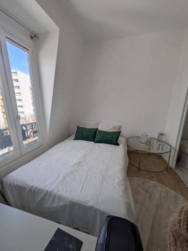 une chambre blanche avec un lit et une fenêtre dans l'établissement Studio Cosy Proche Métro, à Paris