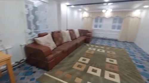 a living room with a brown couch and a rug at Sulaimankul in Kochkorka