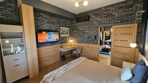a bedroom with a bed and a tv on a brick wall at Apartamenty Kąpielowa Platynowy in Ełk