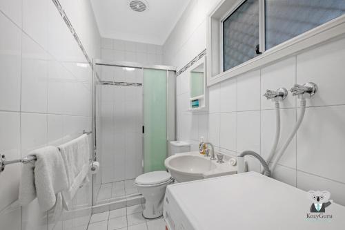een witte badkamer met een toilet en een wastafel bij Fairfield 1B Granny Flat Sleep up to 4 ppl in Fairfield