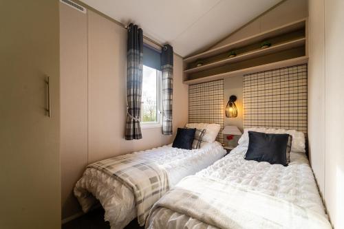 a bedroom with two beds and a window at Wiswell View Lodge: Pendle View Holiday Park in Clitheroe