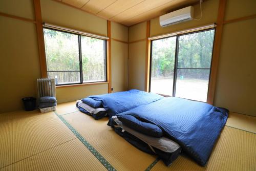 a bedroom with a blue bed in a room with windows at 一棟貸しの宿 OKAYADO in Oshima