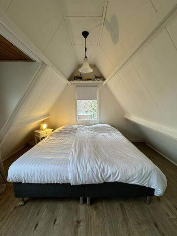 a bedroom with a white bed in a attic at Hello Noordwijk - Tiny House Dahliastraat 60 in Noordwijk