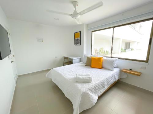 Un dormitorio blanco con una cama con almohadas amarillas y una ventana en Magico Apartaestudio con Piscina 1 Habitacion PR66A en Montería