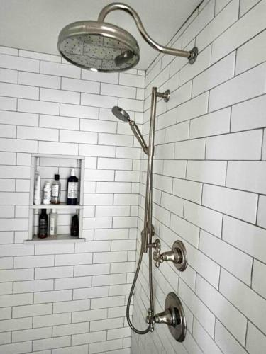 a shower in a bathroom with a white brick wall at Luxury Water-View West End Condo in Provincetown