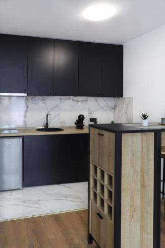 a kitchen with black cabinets and a sink at Tesla Sky Apartment in Ledine