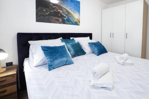 a bed with blue and white pillows on it at Tesla Sky Apartment in Ledine