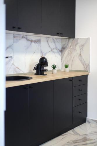 a kitchen with black cabinets and marble walls at Tesla Sky Apartment in Ledine