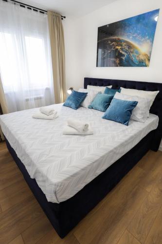 a large bed with blue and white pillows on it at Tesla Sky Apartment in Ledine