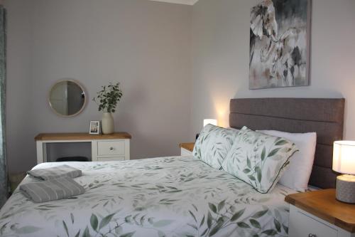 a bedroom with a bed and a table with a mirror at Sunrise Cottage in Llanddulas