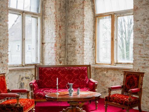 a living room with a red couch and a table at Zamek Międzylesie in Międzylesie