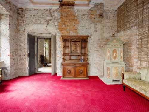a room with a red carpet and a wooden cabinet at Zamek Międzylesie in Międzylesie
