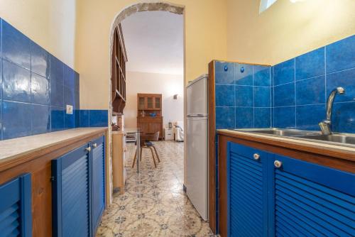 a kitchen with blue tiled walls and a refrigerator at Burantì Guest House in Alghero