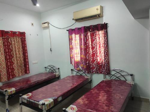 twee bedden in een kamer met rode gordijnen bij N k ladies PG in Chennai