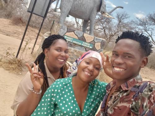 a group of people posing for a picture with an elephant in the background at Safari Junction Backpackers hostel in Iringa