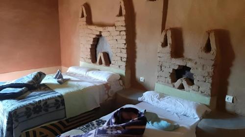 a room with two beds and a baby laying on the bed at Auberge Dinosaur Kem Kem in Tafraoute Sidi Ali