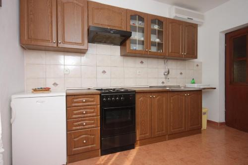 a kitchen with wooden cabinets and a black stove top oven at Apartments with a parking space Sali, Dugi otok - 910 in Sali