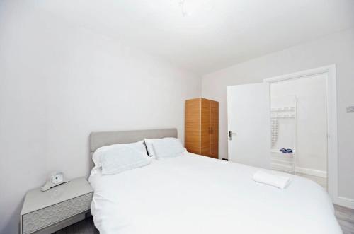 a white bedroom with a bed and a desk at Chic 1BR Thornton Flat - Charm and City Access in Thornton Heath