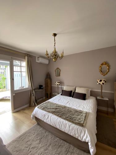 a bedroom with a large bed and a chandelier at La Villa du Grand Large in Biscarrosse