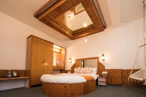 1 dormitorio con 1 cama grande y espejo grande en The Village Manali-TVM, "Bunrise" Cafe, "Old Town Tavern" Pub, en Manali